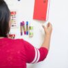 Woman hanging up notebook on smart magnetic plastered wall